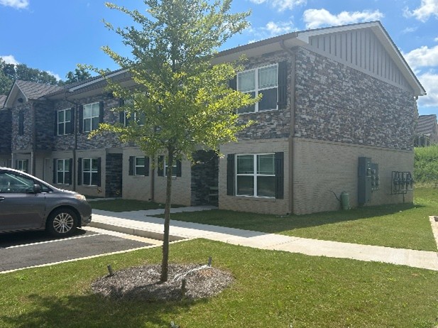 Shows the entrance and parking of a series of apartment buildings that contain parking stalls beneath them